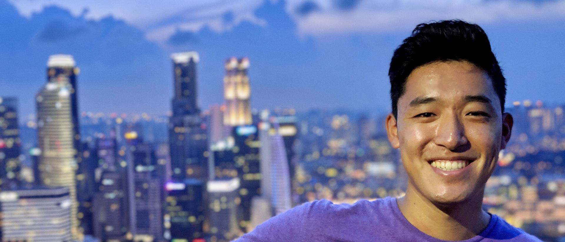 A young male student in front of a city skyline