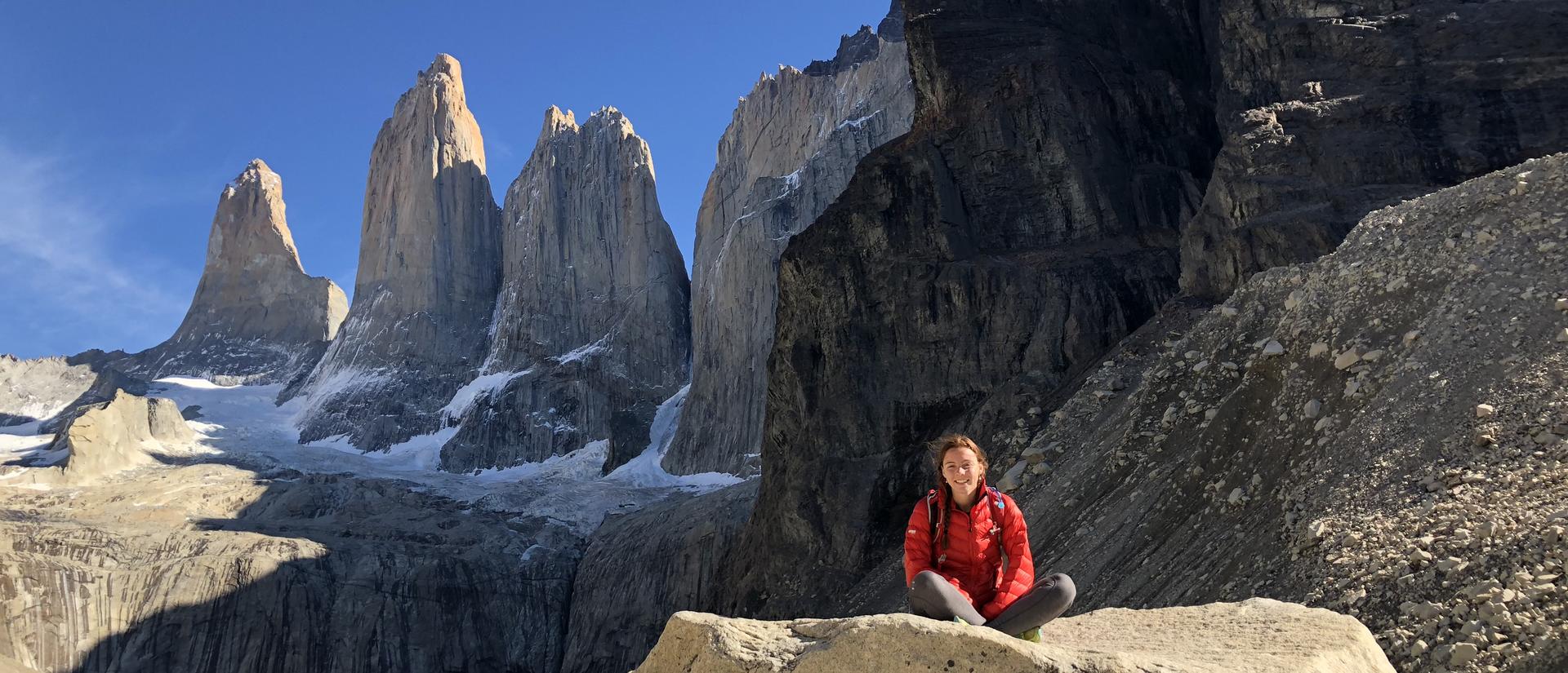 Hiker sitting on a rock before mountain peaks