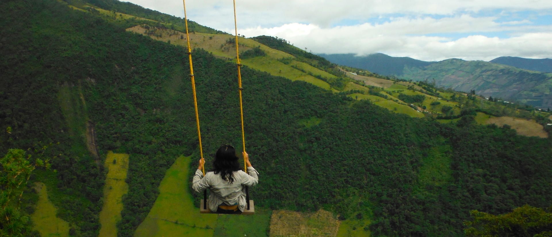 Person swinging over a green mountain valley