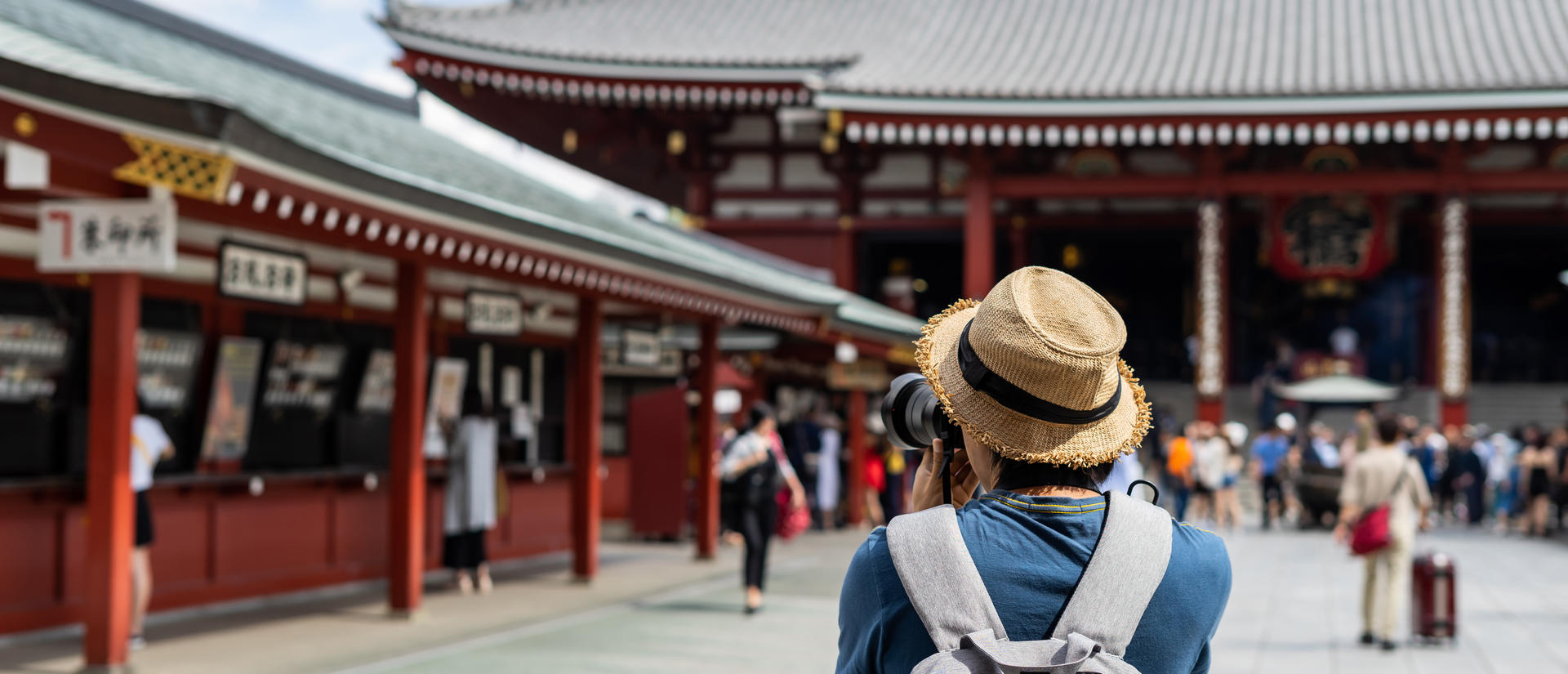 A traveler with a backpack and camera photographs a traditional temple.