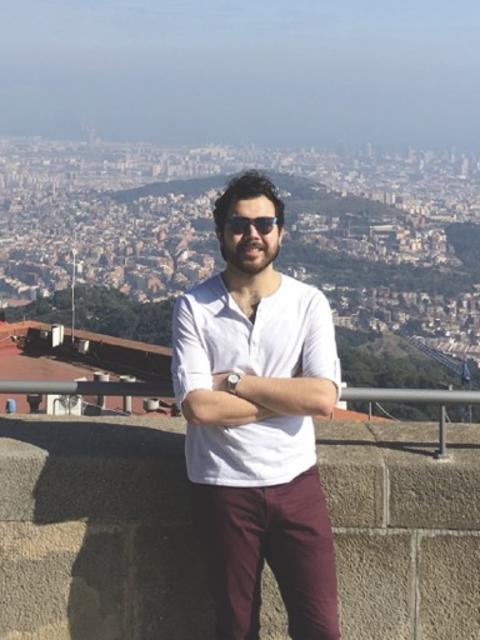 A person leans on a stone railing with a panoramic view of Barcelona stretching out behind them.